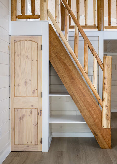 stairs to loft with log post and railing and closet under steps